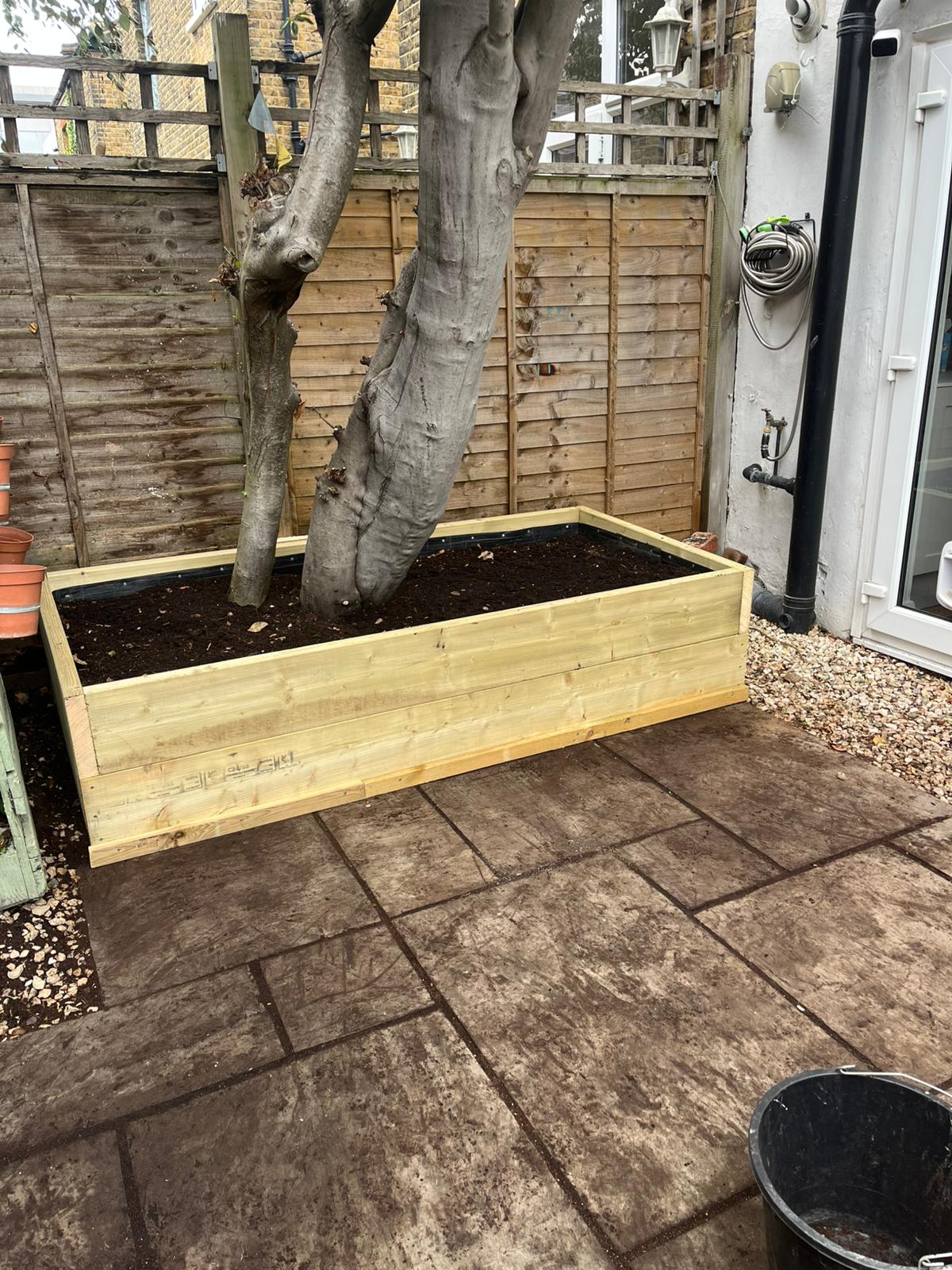 Timber sleeper planter built around a mature tree on an existing patio.