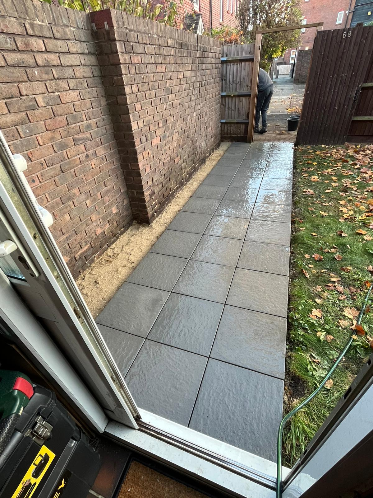 Straight grey slab path running from a back door to the garden gate.