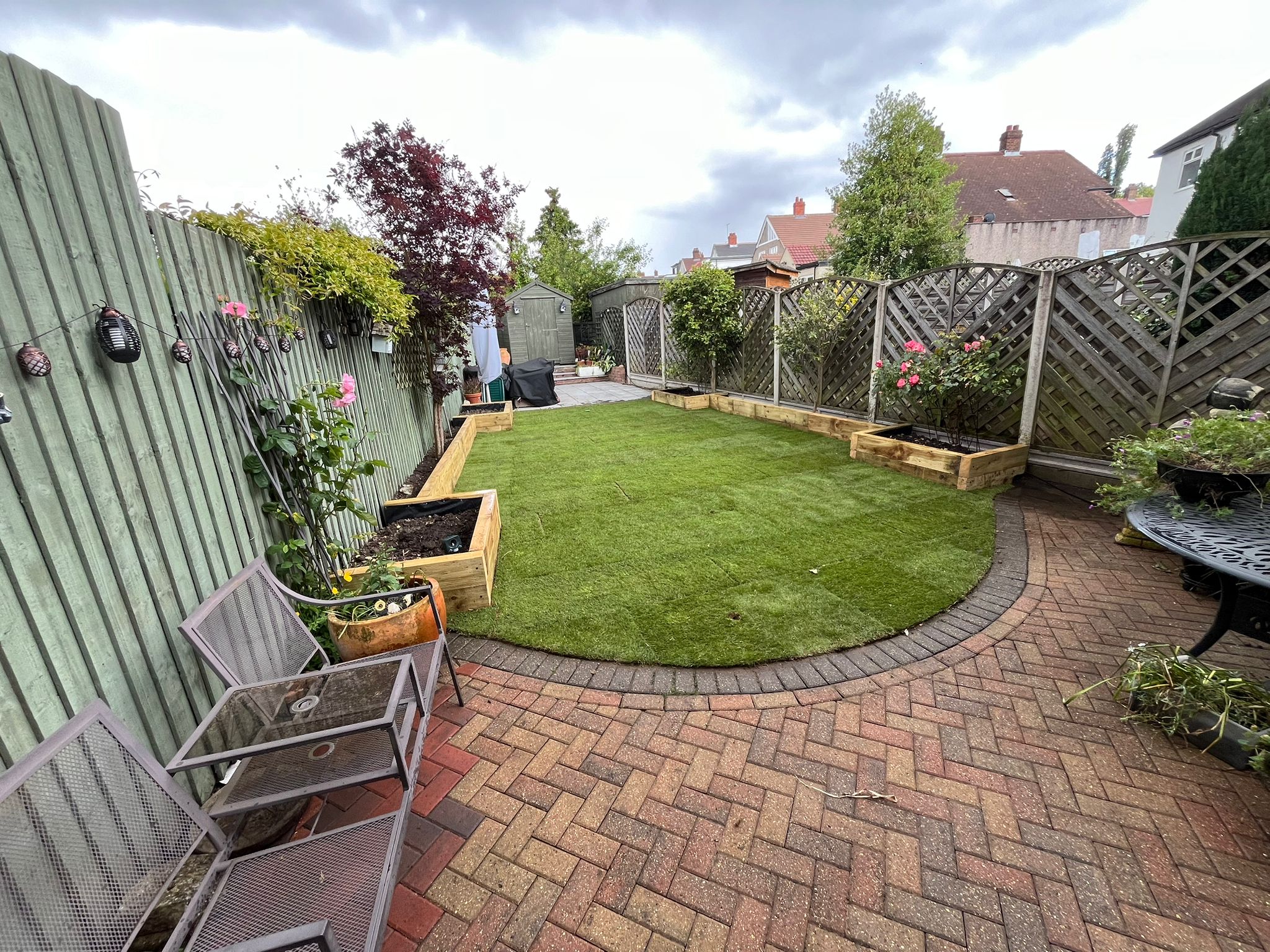 Curved circular lawn edged with block paving in a cottage-style garden.