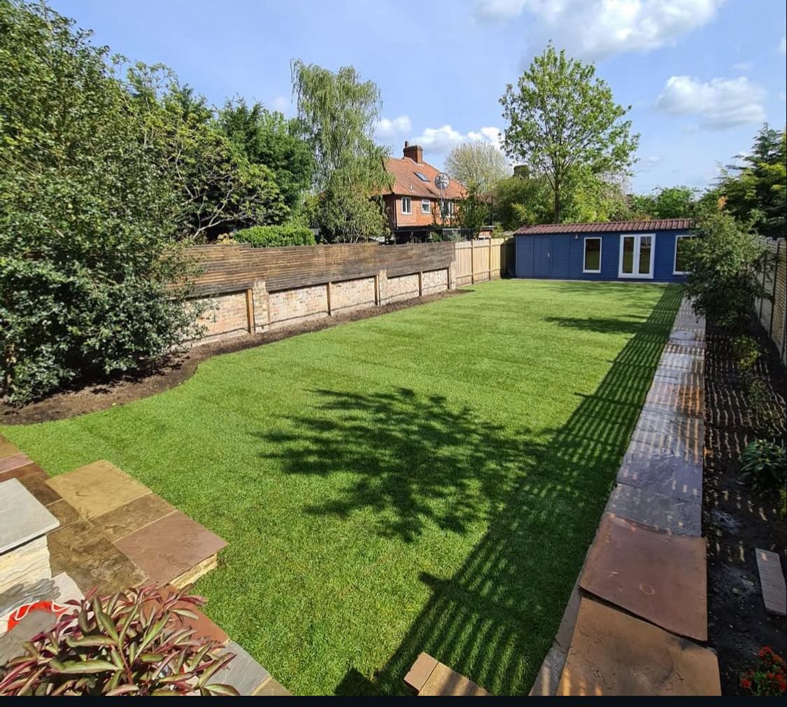 Long, flat lawn with simple timber fencing and a shed at the end.